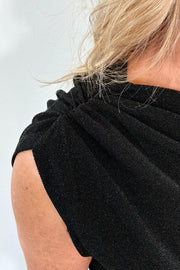 Close-up of a person wearing a black sleeveless top against a white background