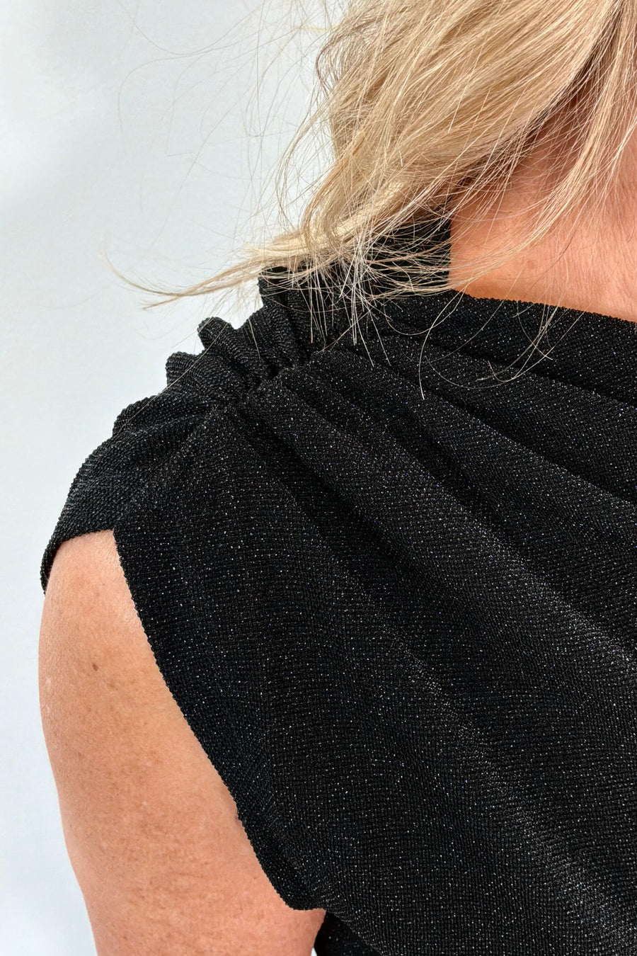 Close-up of a person wearing a black sleeveless top against a white background