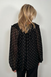 Back view of a woman wearing a sheer polka dot blouse