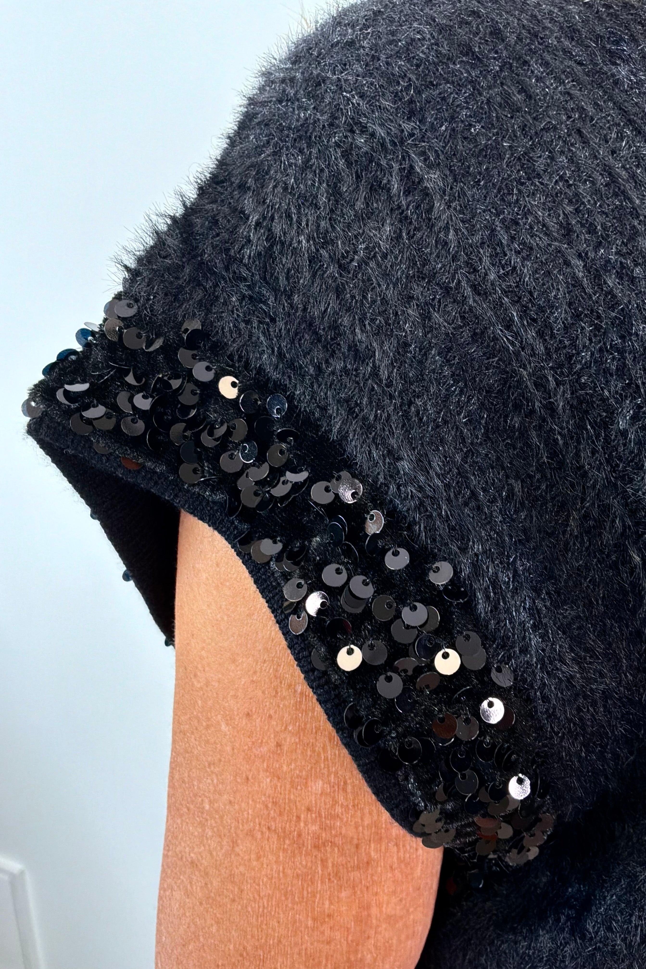 close-up of a black fuzzy cap sleeve embellished sweater