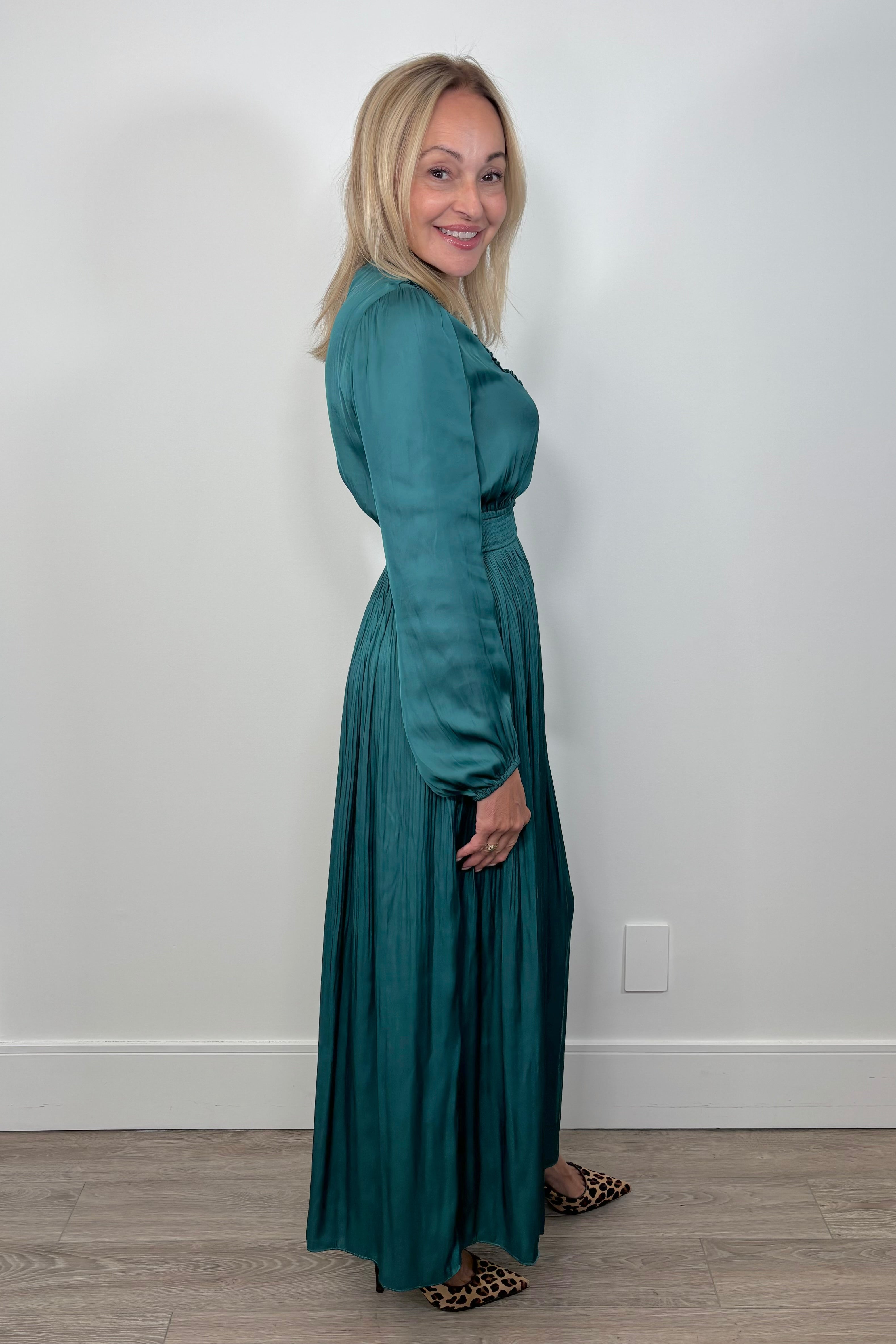 Side view of woman wearing a green maxi long sleeve silk dress