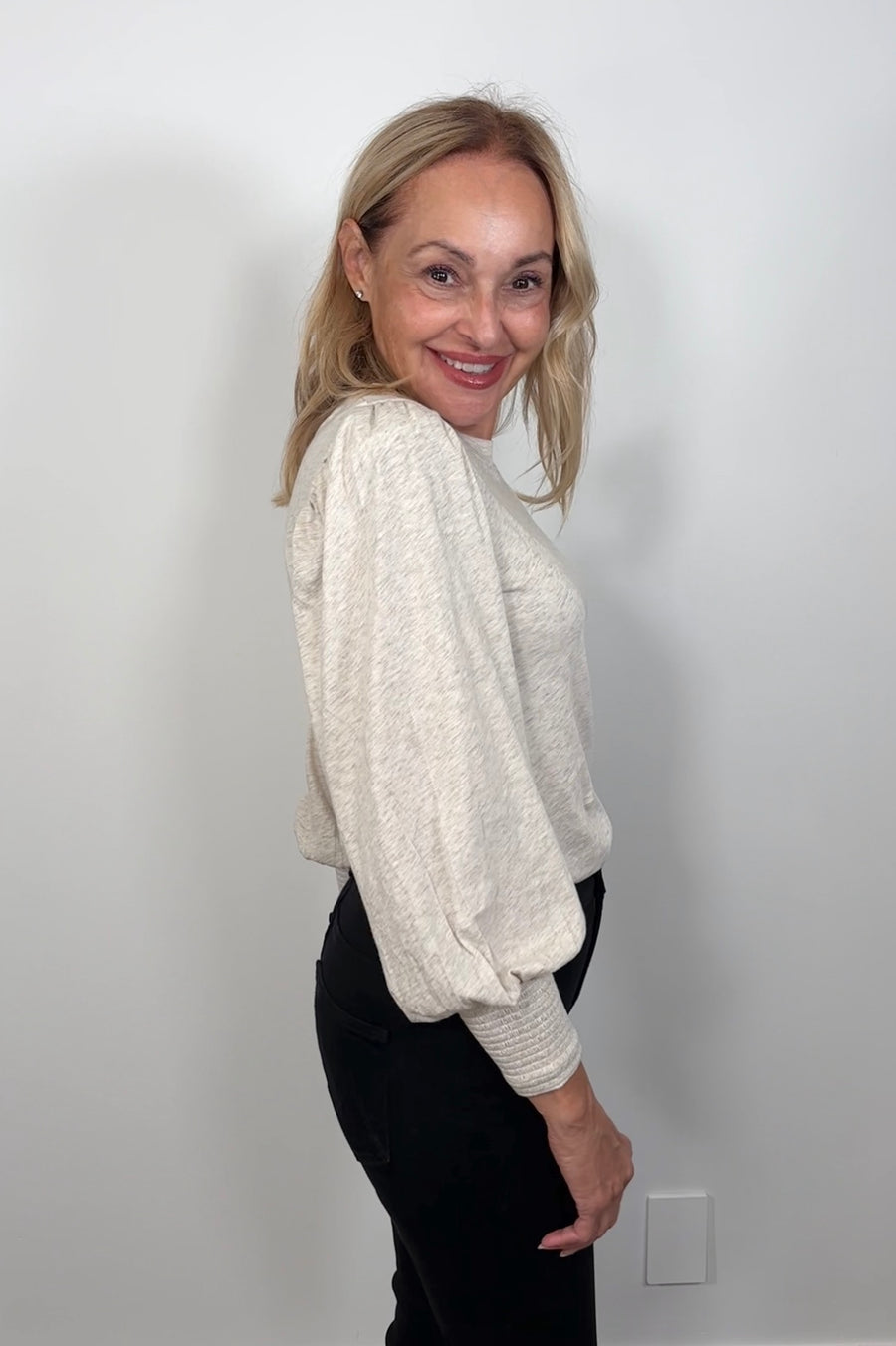 Side view of woman wearing a blouson cuffed sleeve beige top