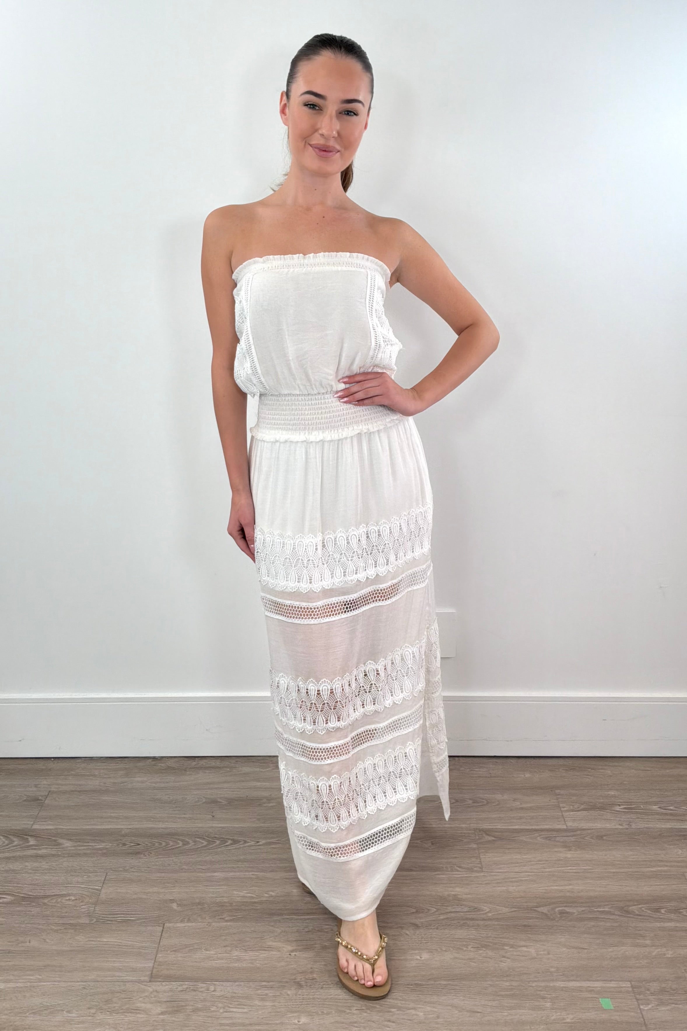 woman wearing a maxi strapless white dress with lace details in the skirt