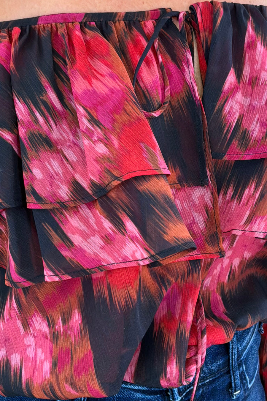 Close-up of a colorful patterned top with pink and black design.