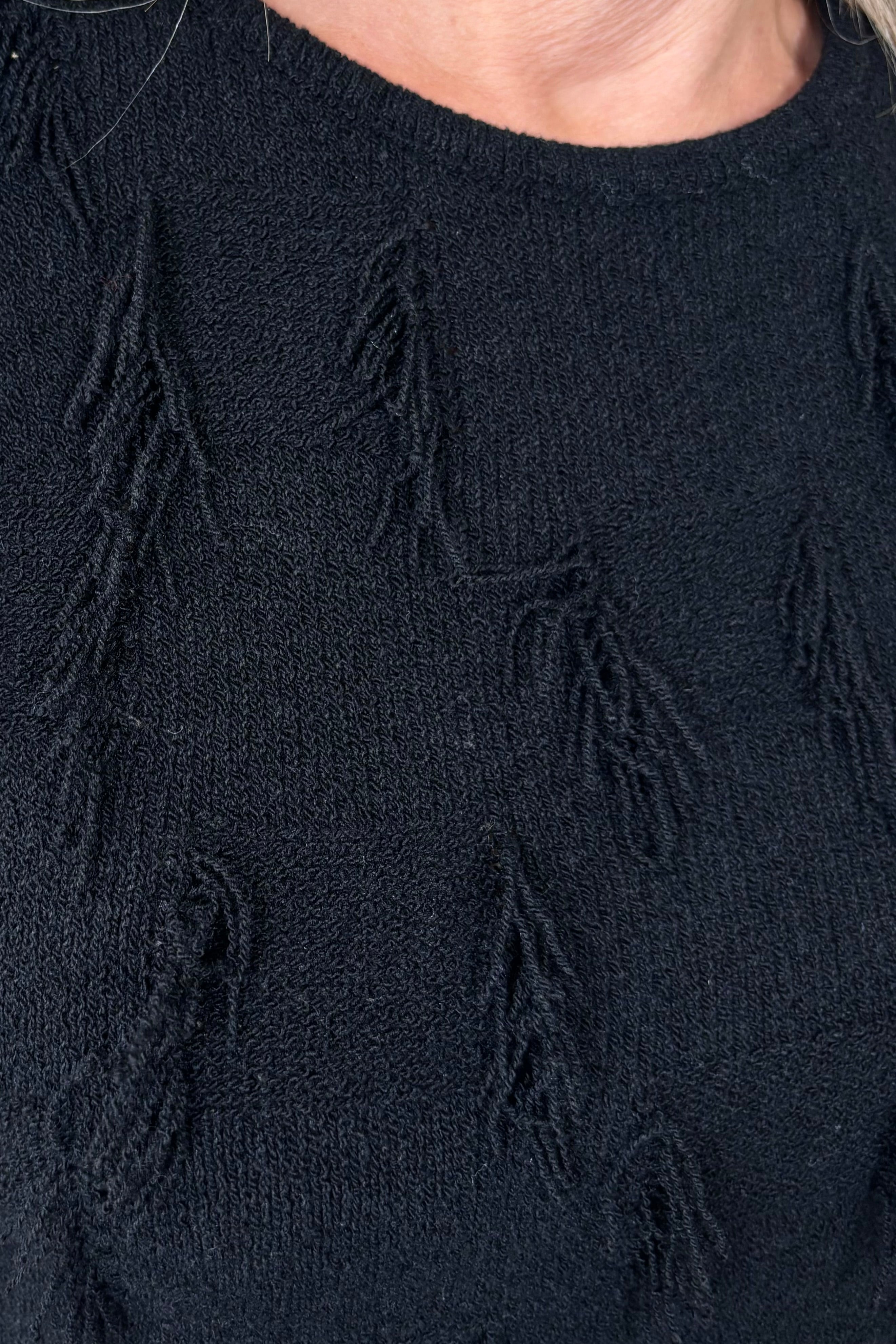 Close up of the beck of a black tank top with fine gauge fringes 