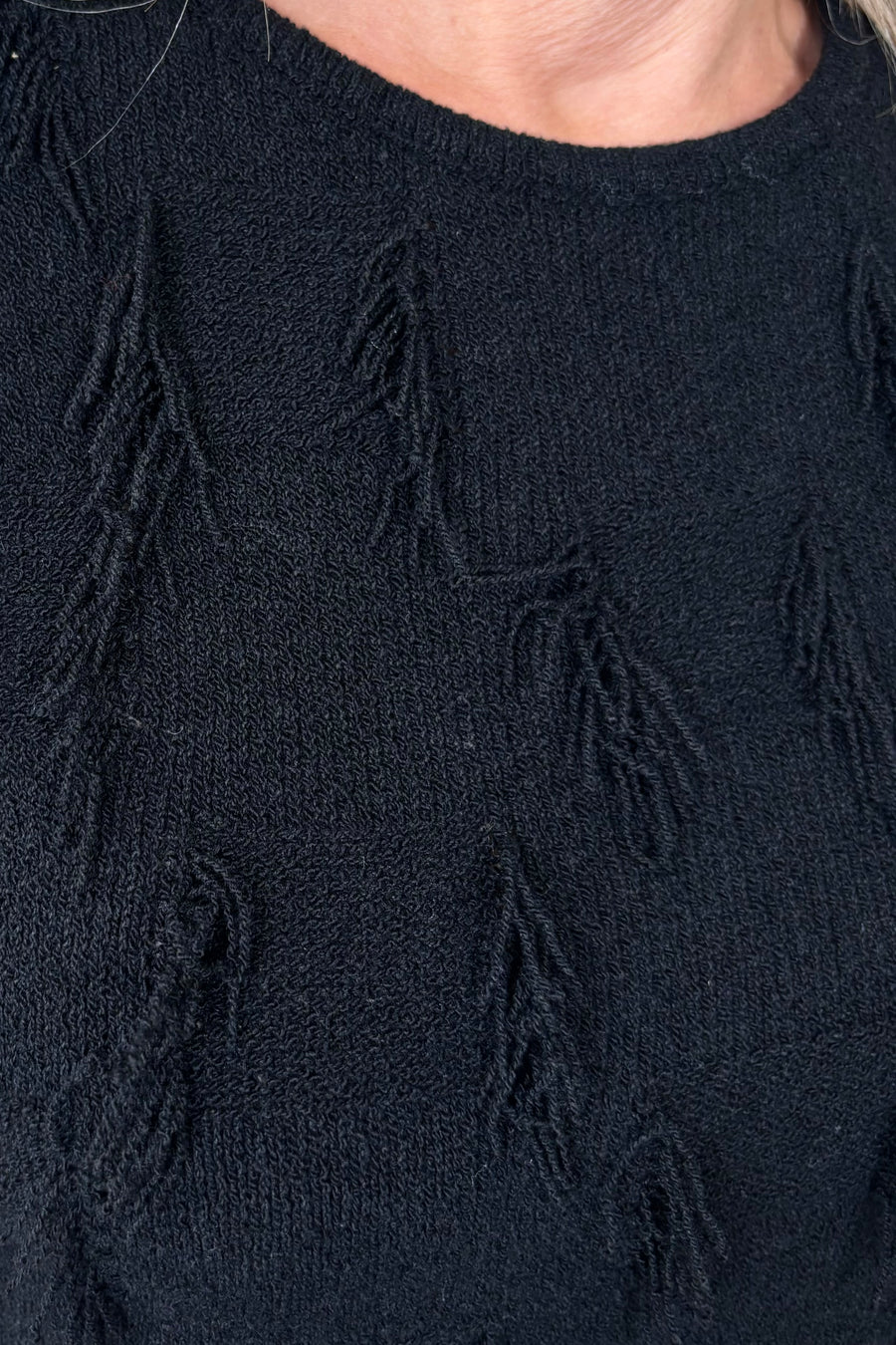 Close up of the beck of a black tank top with fine gauge fringes 