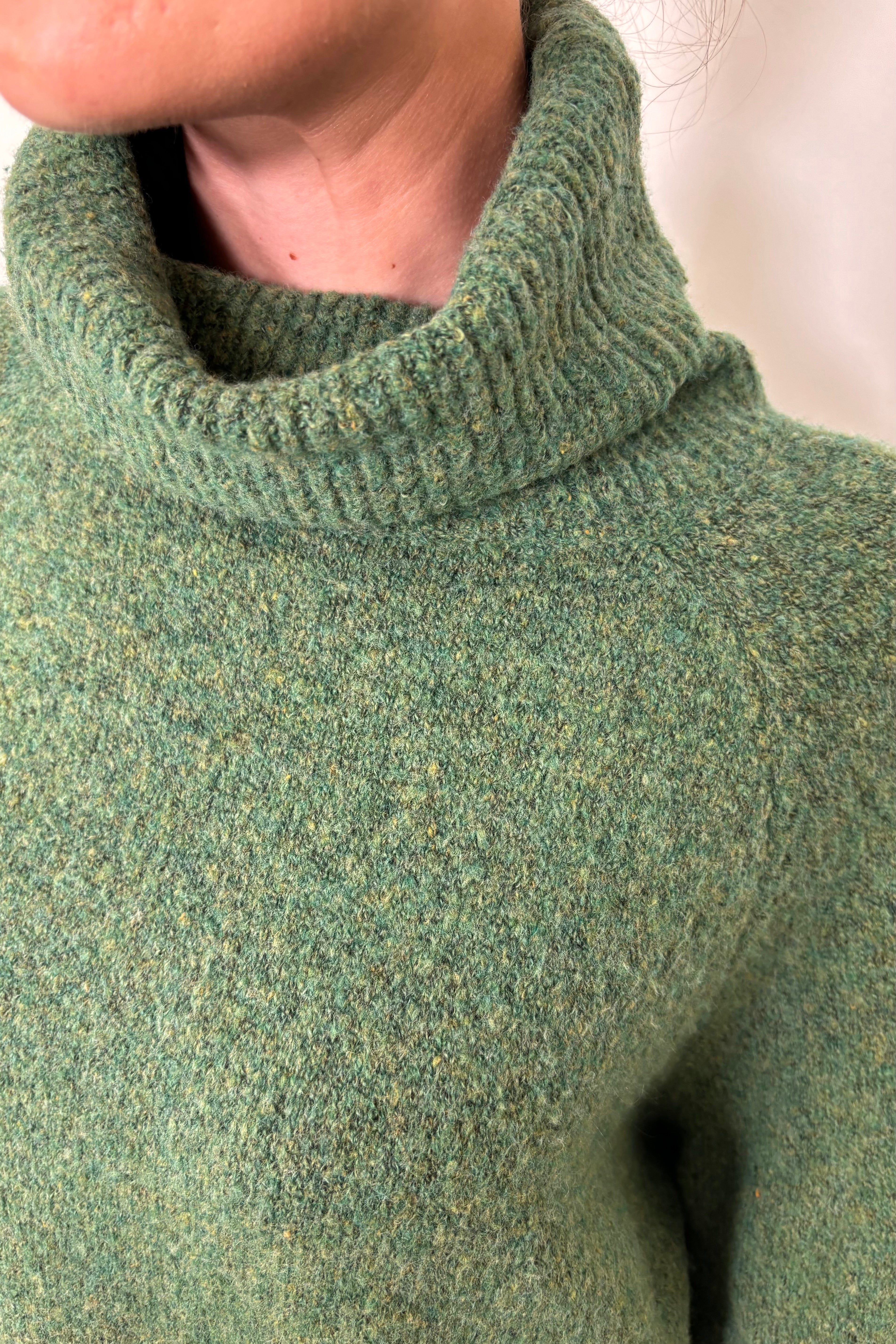 Close up of the turtle neck of an oversized green knitted turtleneck 