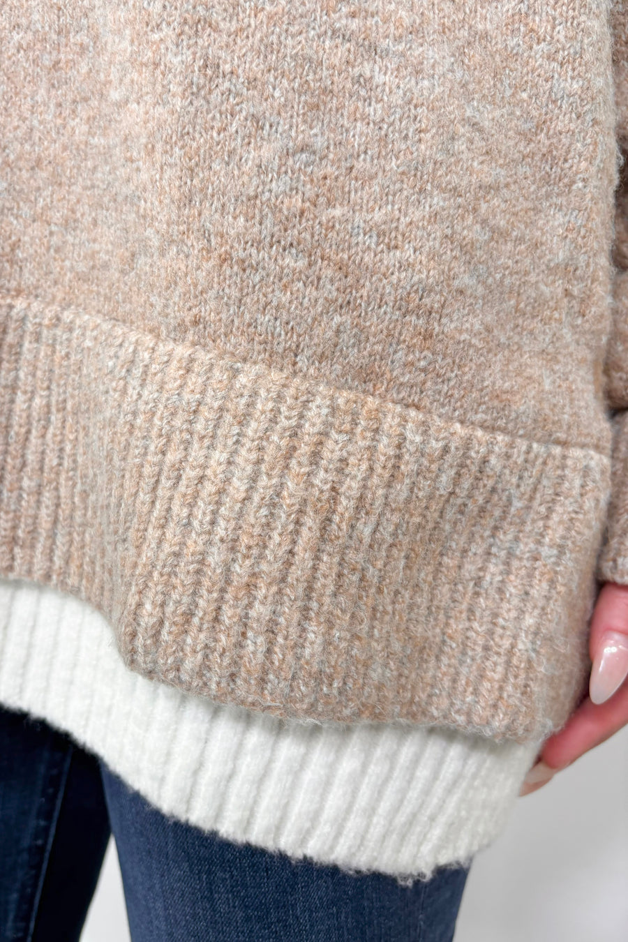 close up of the bottom of a beige and white sweater