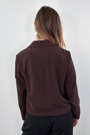 Woman wearing a brown blazer with tie detail at bottom 