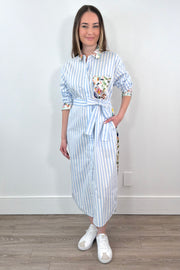 Woman wearing a white and blue striped dress with a silk floral patterns belted