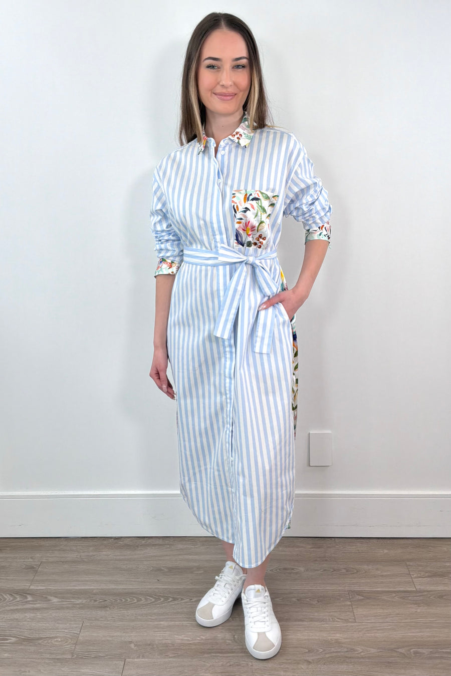 Woman wearing a white and blue striped dress with a silk floral patterns belted