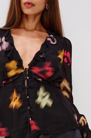 close-up of a woman wearing a black top with blurred floral pattern