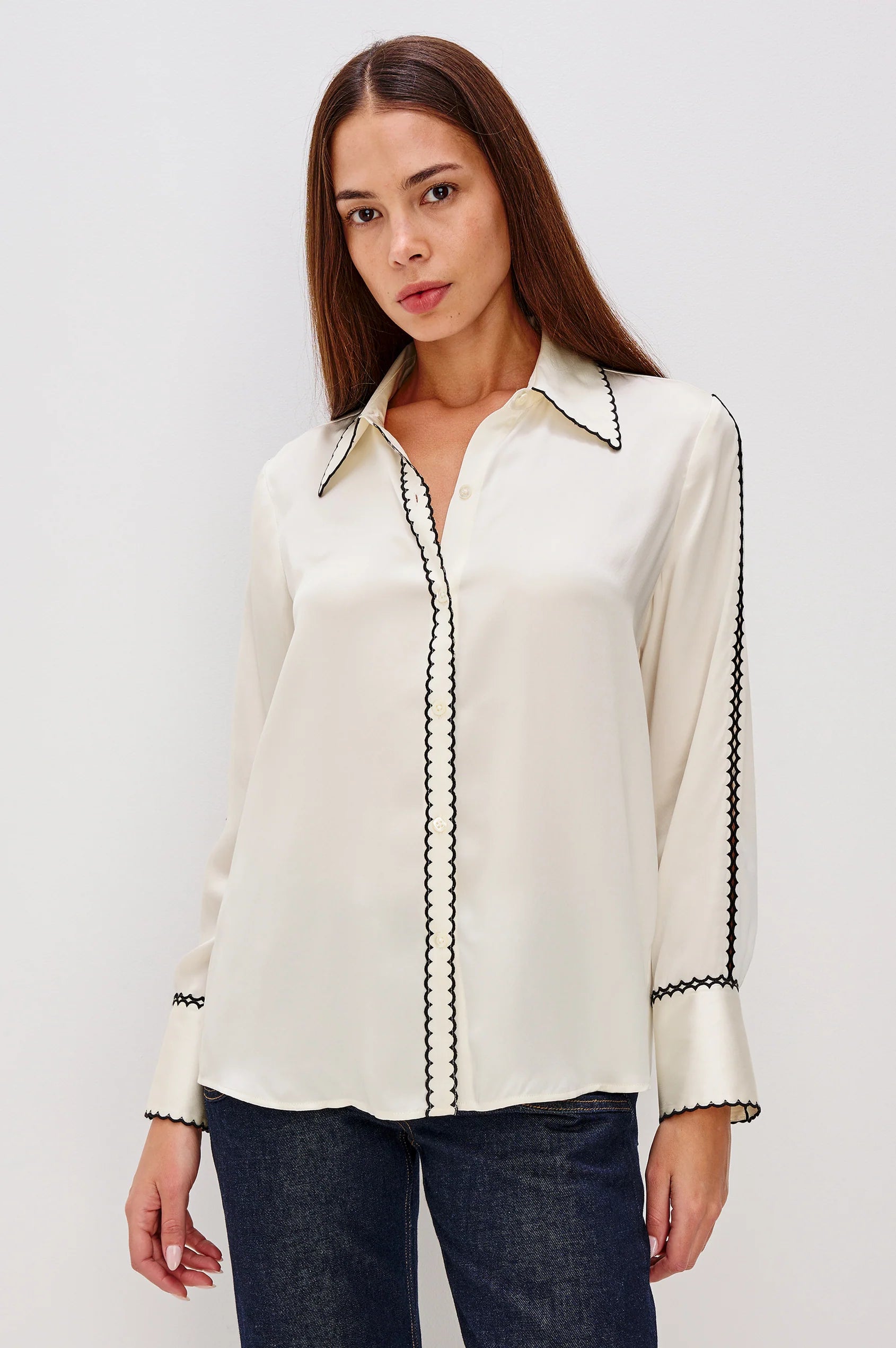 woman wearing a silk cream blouse with black stitching