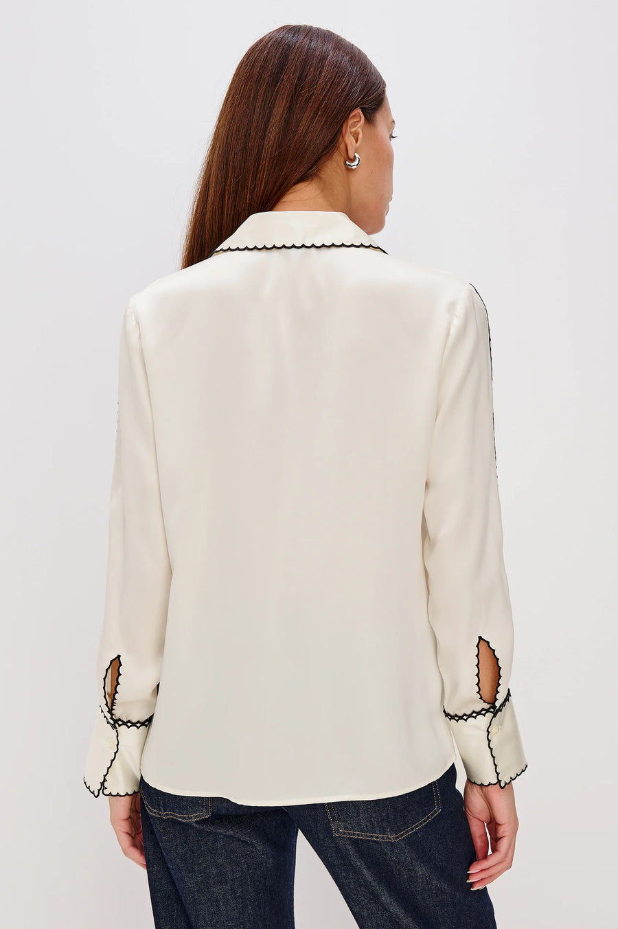 woman wearing a silk cream blouse with black stitching