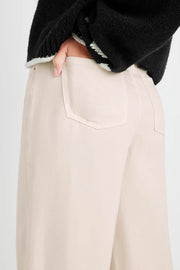 Beige pants worn by a person with a black sweater on a light gray background