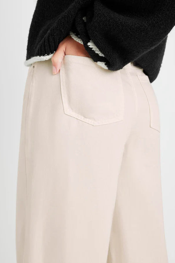 Beige pants worn by a person with a black sweater on a light gray background