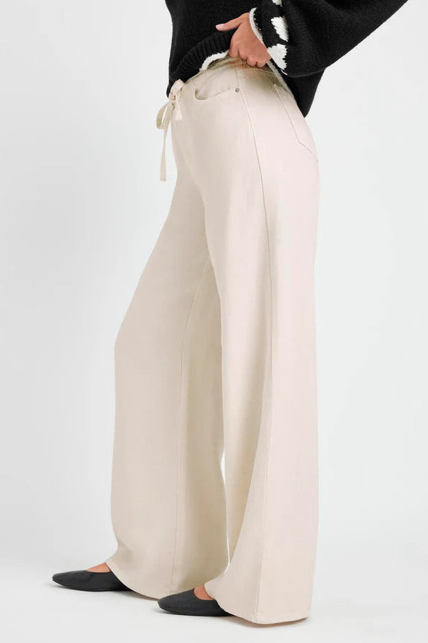 Person wearing beige wide-leg pants on a white background