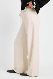 Person wearing beige wide-leg pants on a white background