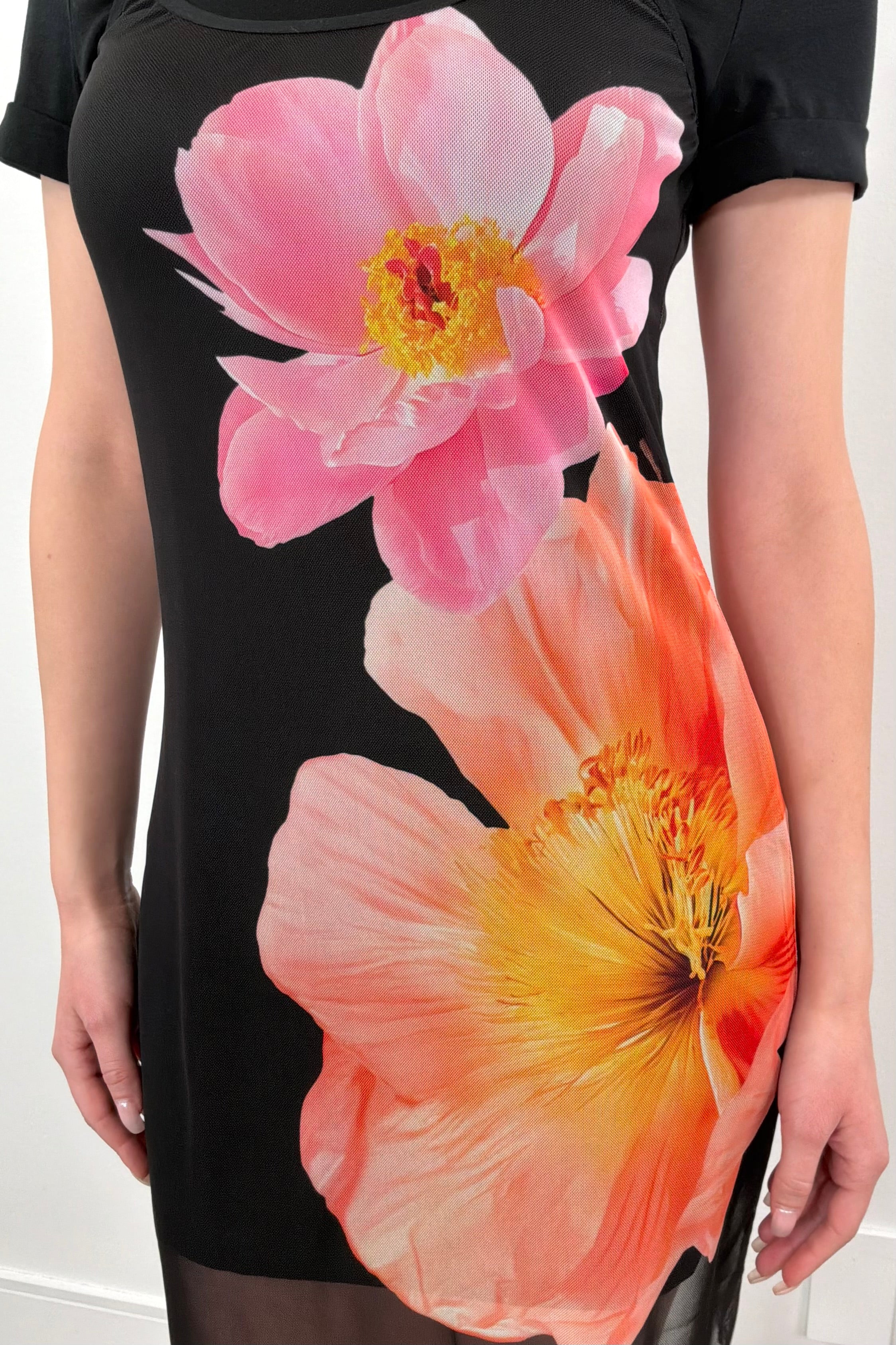 Close-up of a black dress with a mesh dress on top that has a floral design