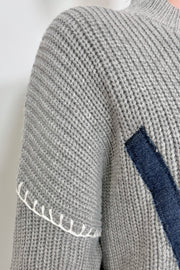 Close up of the shoulder of a gray sweater with whipstitch detailing