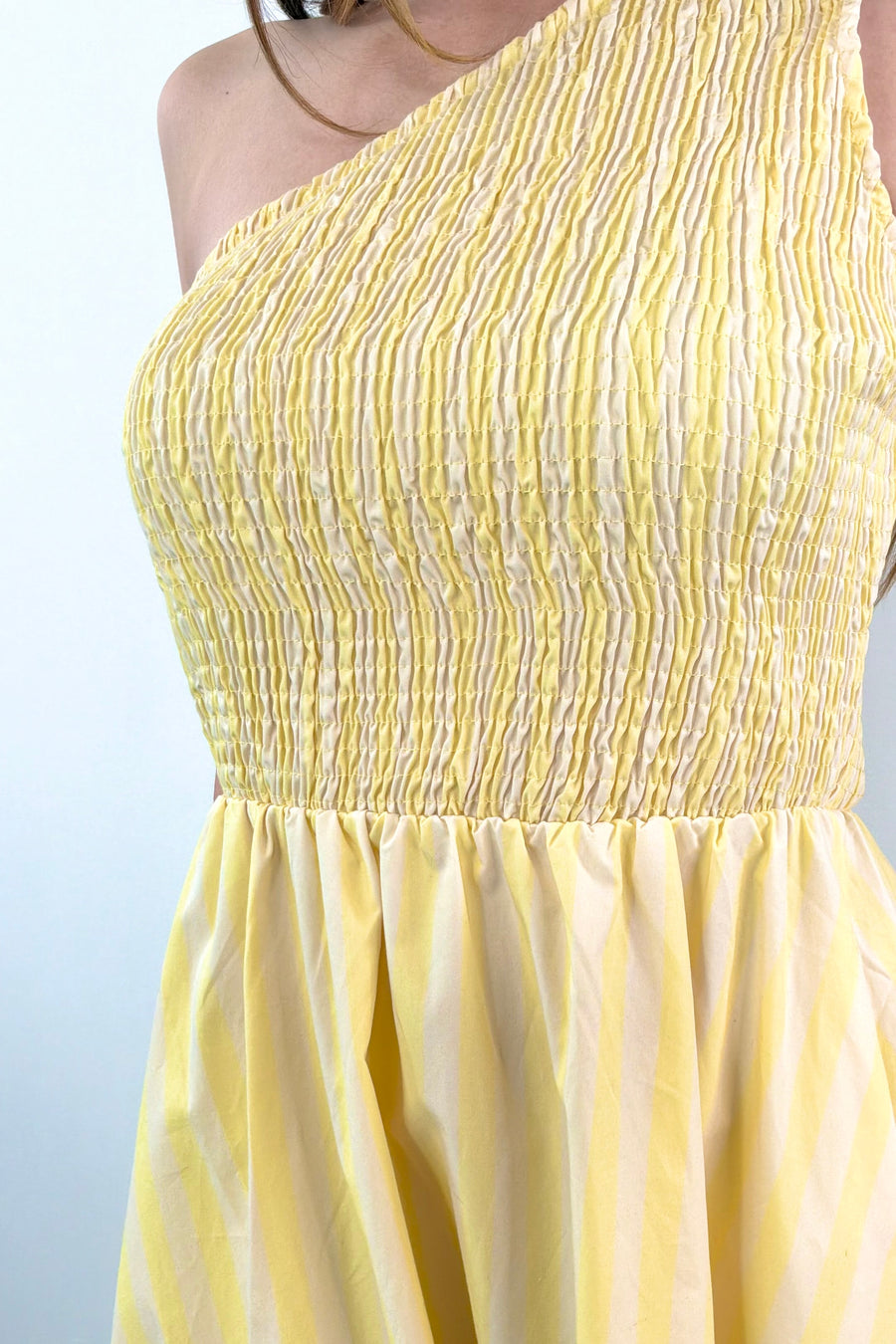 close-up of a one-shoulder elastic torso yellow and white stripped dress