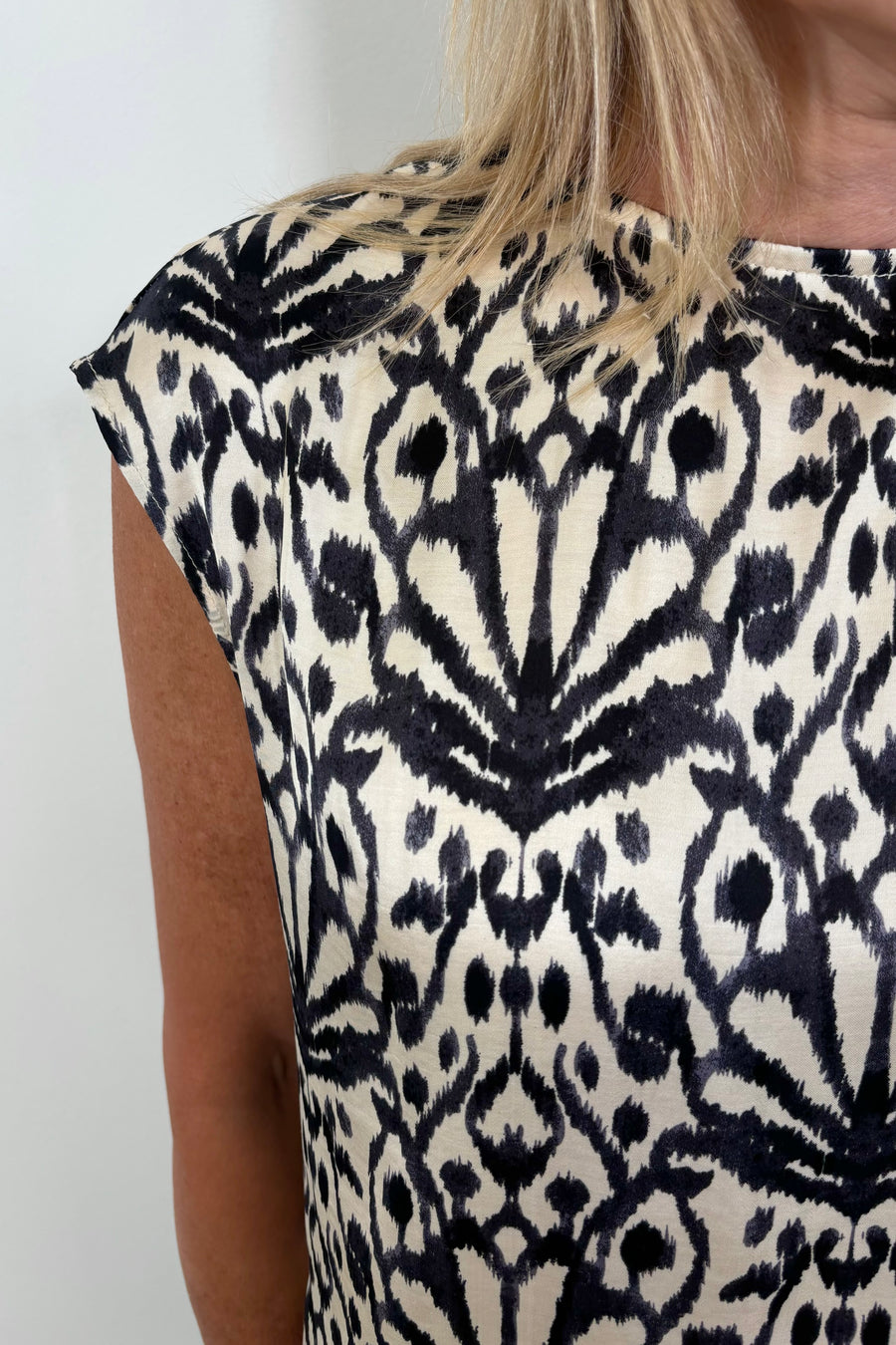 Close up of the shoulder of a woman wearing a printed satin sleeveless top 
