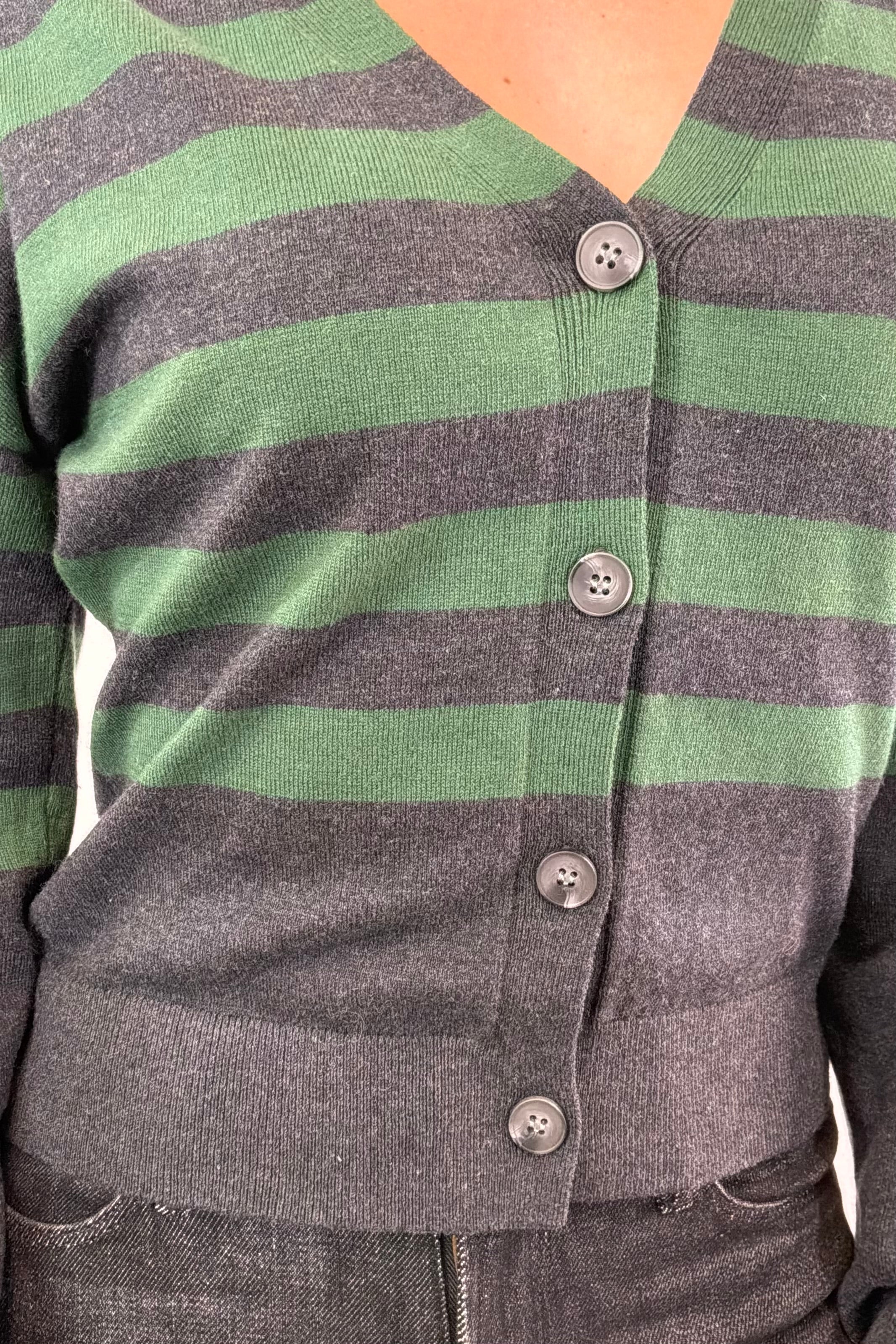 Close up of woman wearing a black and dark green striped cardigan with black buttons