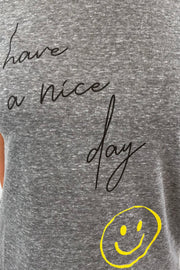 close-up of a gray t-shirt with 'Have a nice day' text and smiley face design