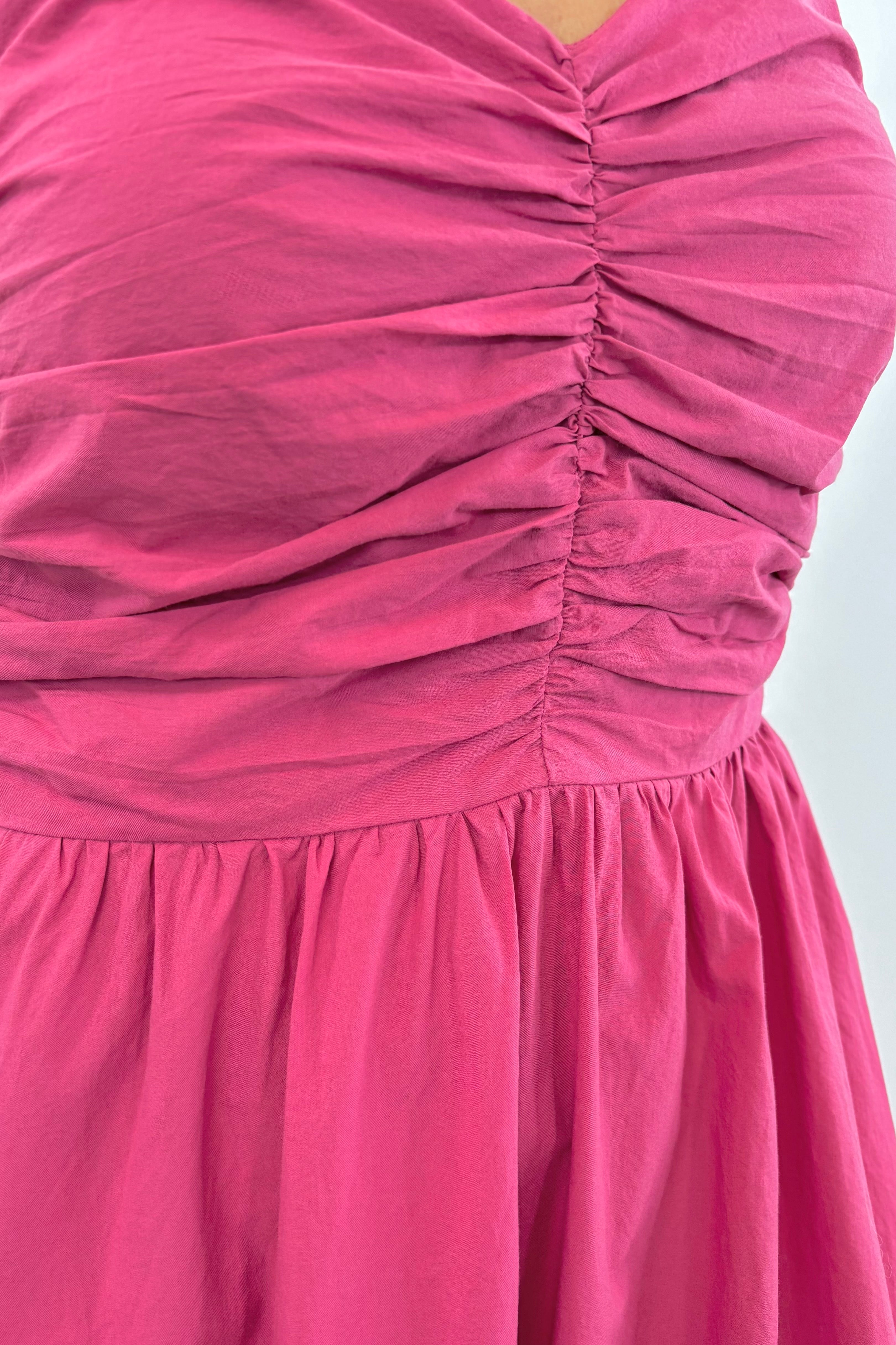 Close up of Woman wearing a dark pink midi dress with a ruffled chest