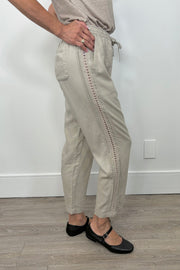 Side view of woman wearing a cool beige straight pant with detailing on the side