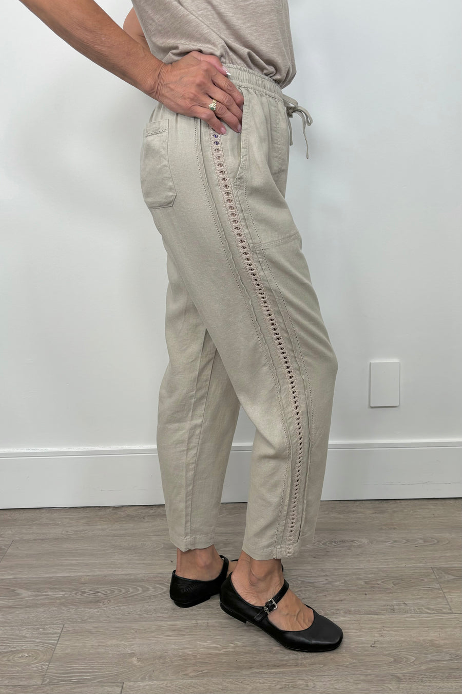 Side view of woman wearing a cool beige straight pant with detailing on the side
