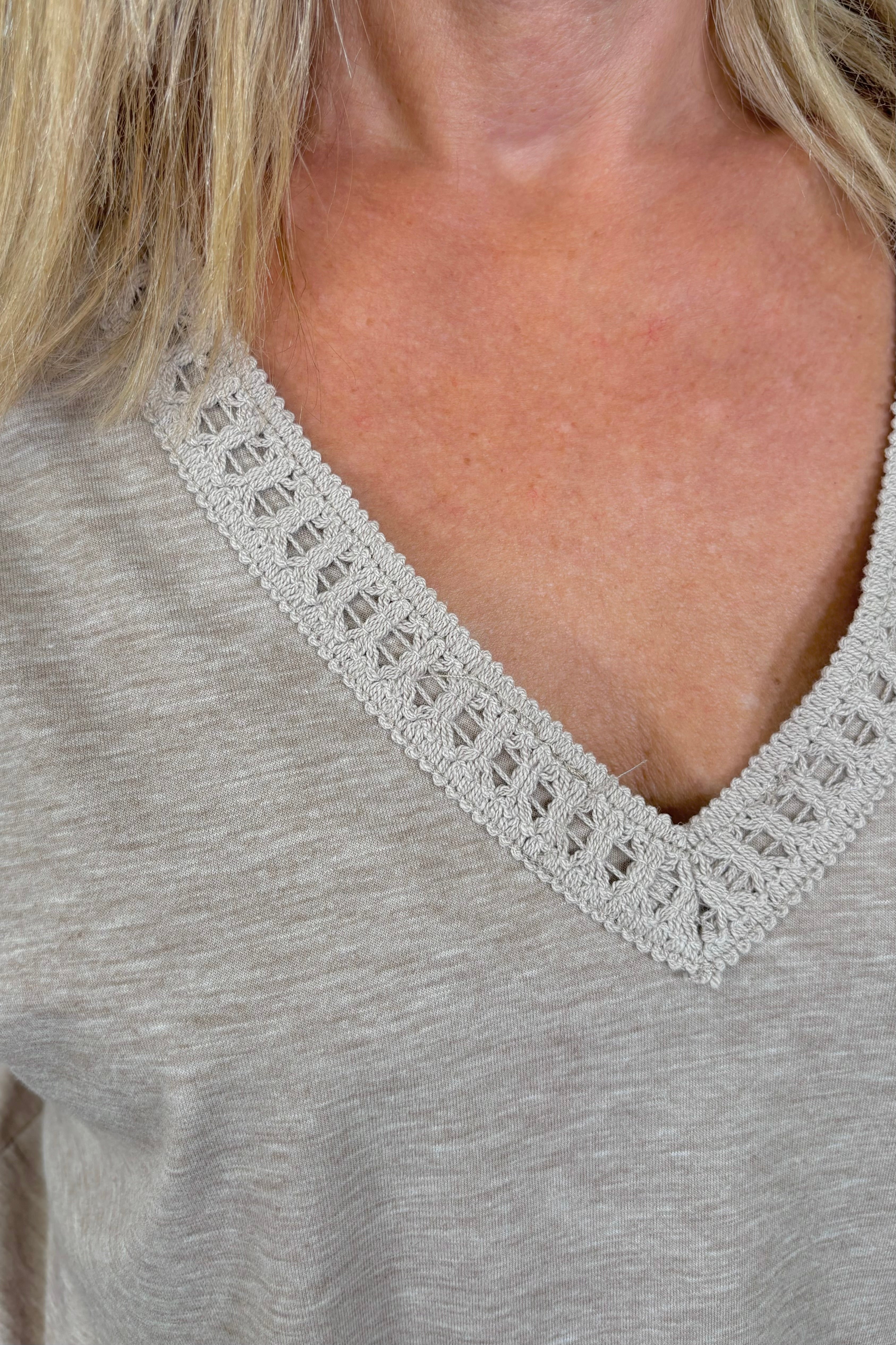 Close up of the neck of woman wearing a cool beige v-neck tee