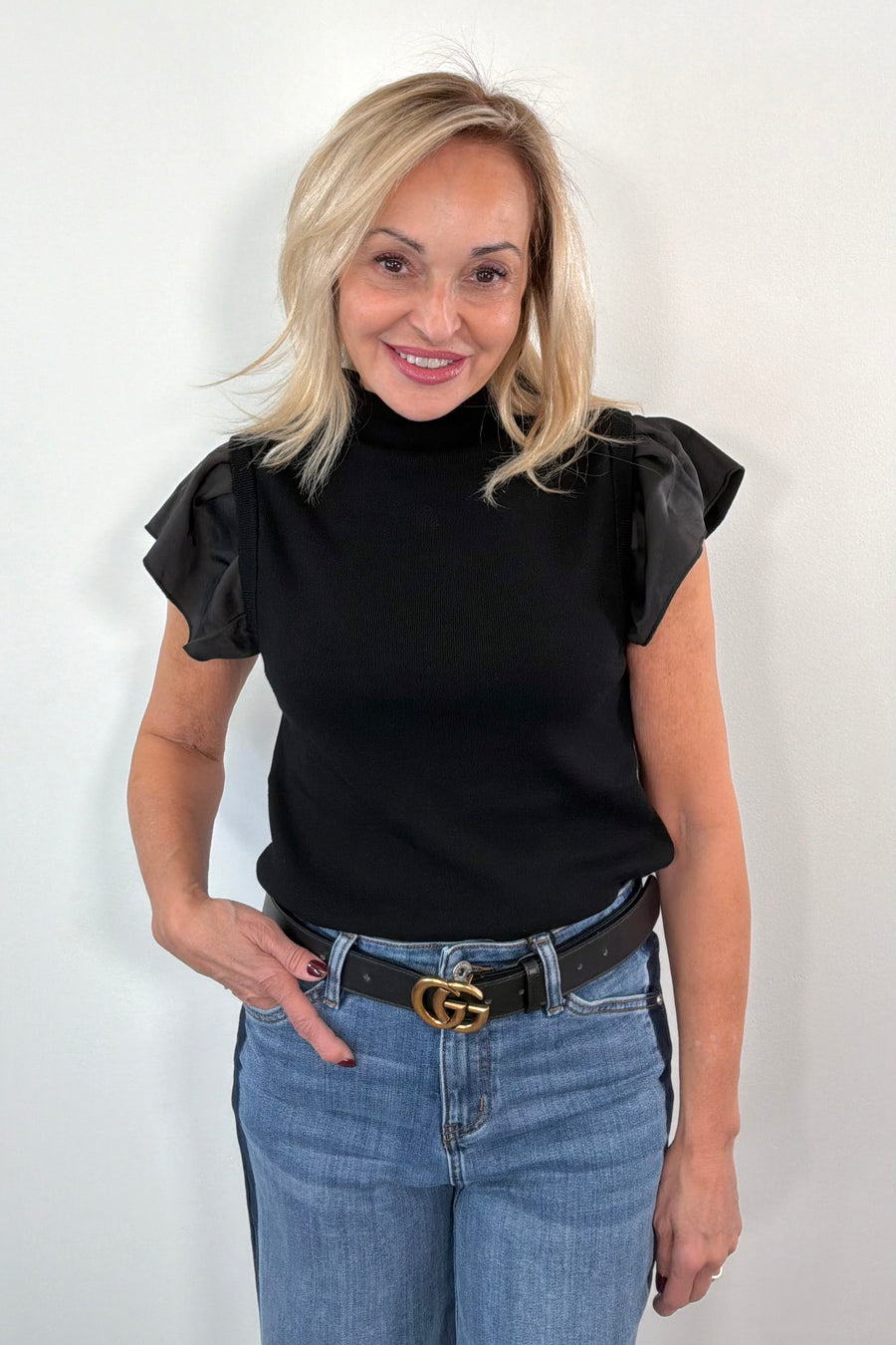 woman wearing black sweater top with ruffle satin cap sleeves