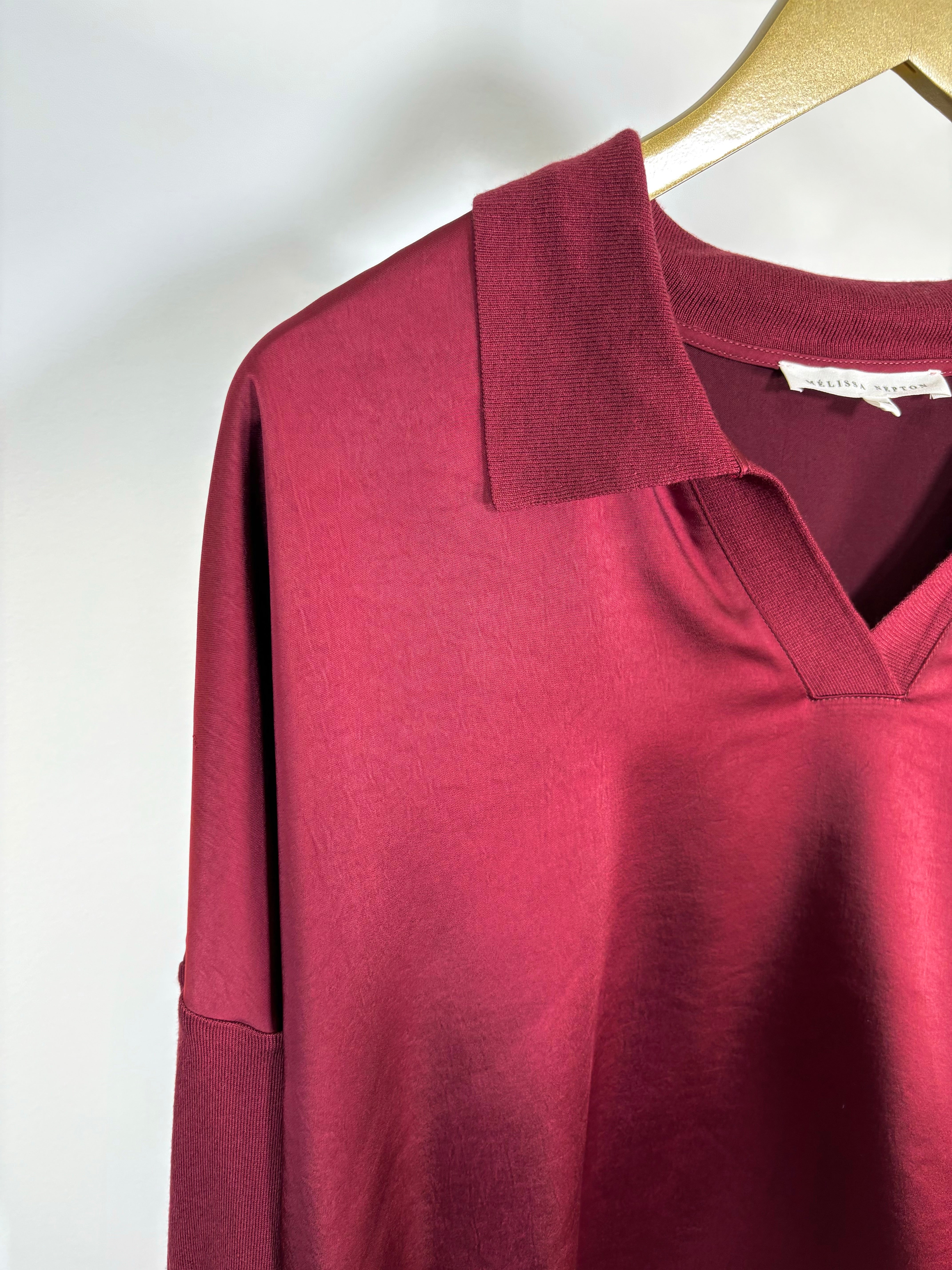 Close-up of the collar of a red wine long sleeve satin top
