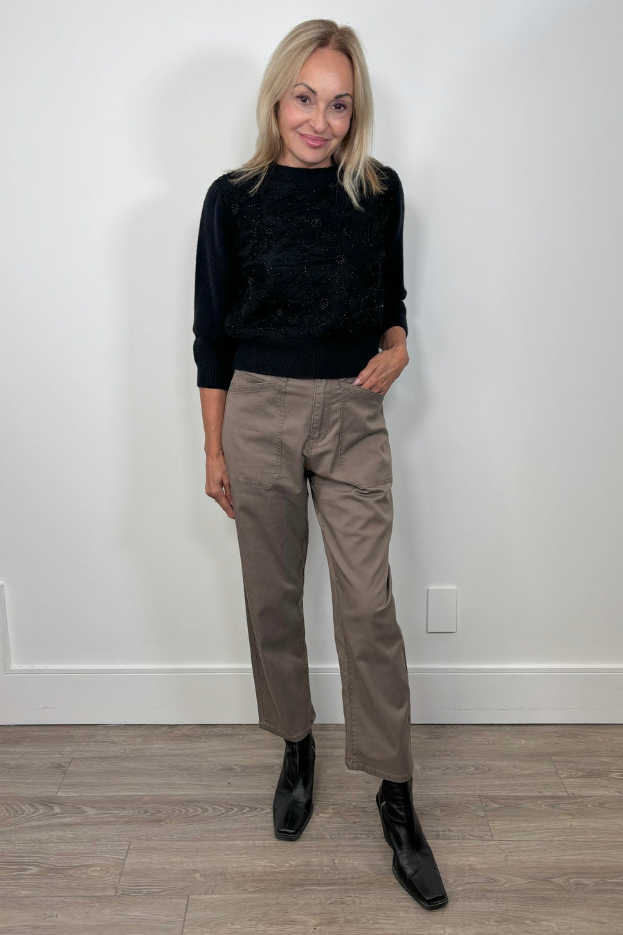Front view of woman wearing a pale brown pant with a black long sleeve top