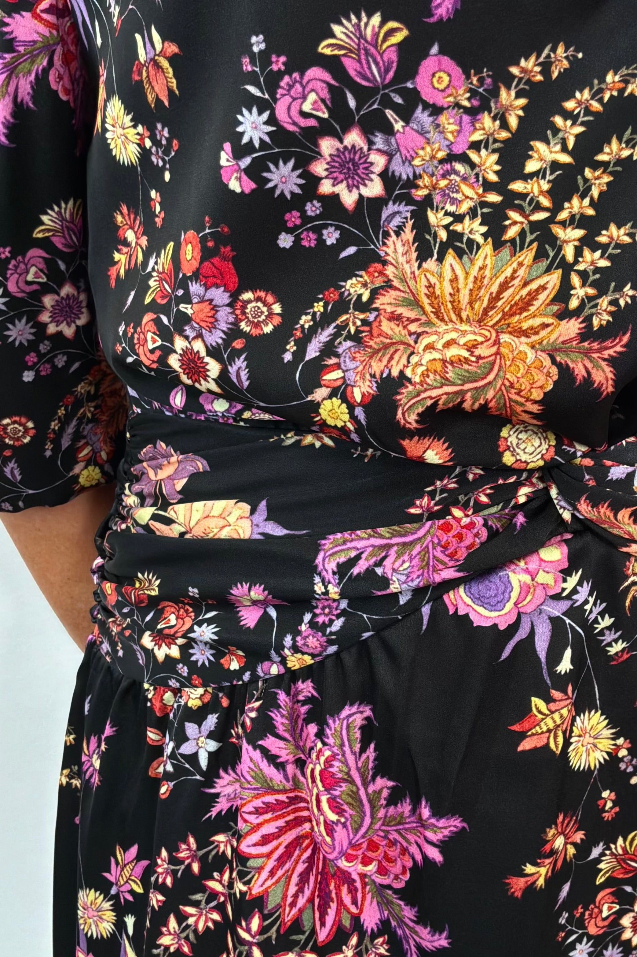 Close-up of a black dress with colorful floral pattern on a white background