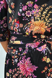 Close-up of a black dress with colorful floral pattern on a white background