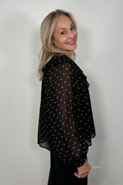 Side view of a woman wearing a sheer polka dot blouse