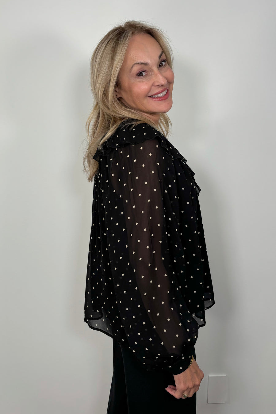 Side view of a woman wearing a sheer polka dot blouse