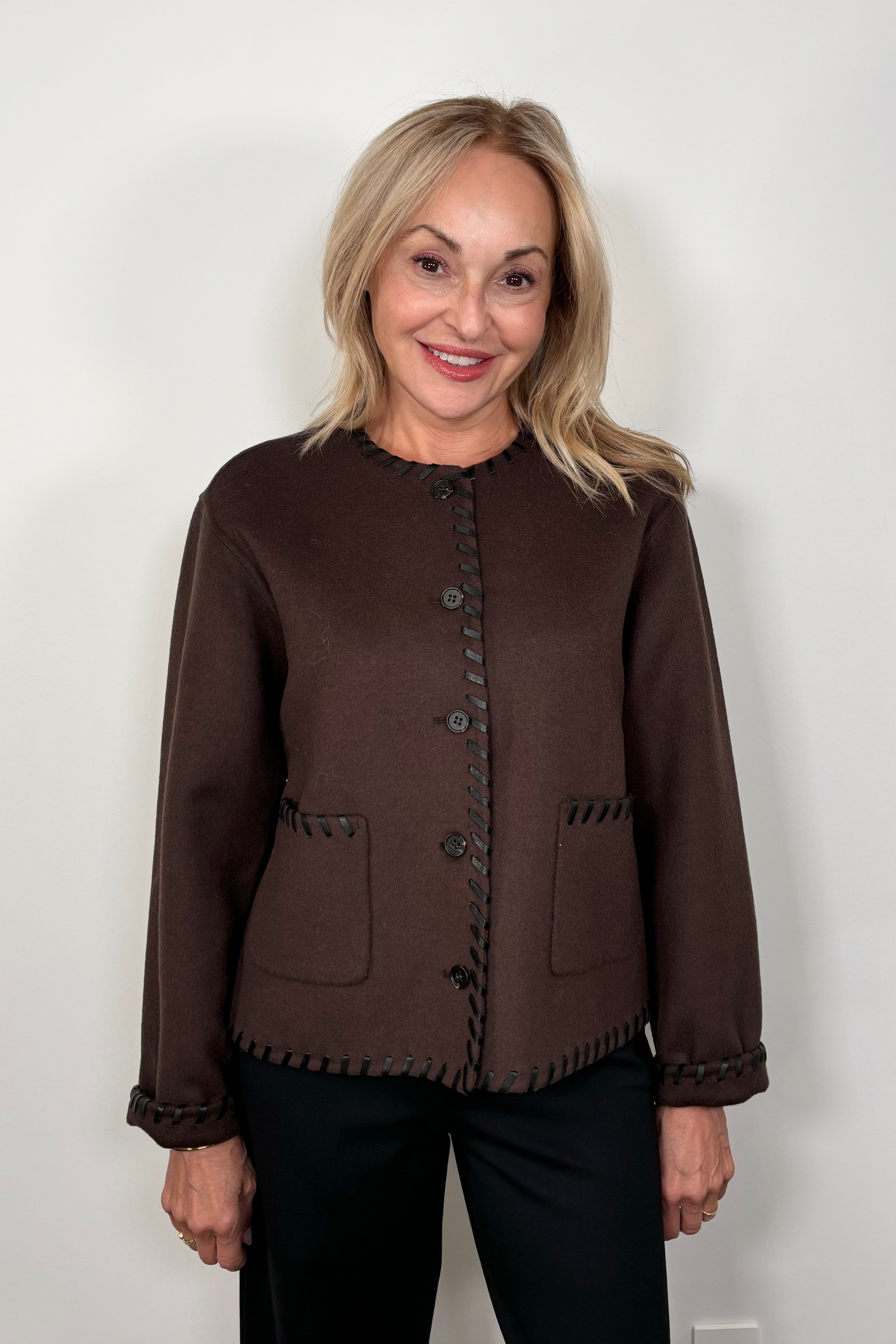 Front view of woman wearing a buttoned up brown wool with whipstitch detailing