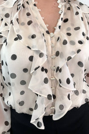 close-up of a sheer ruffle blouse with polka dots tucked in
