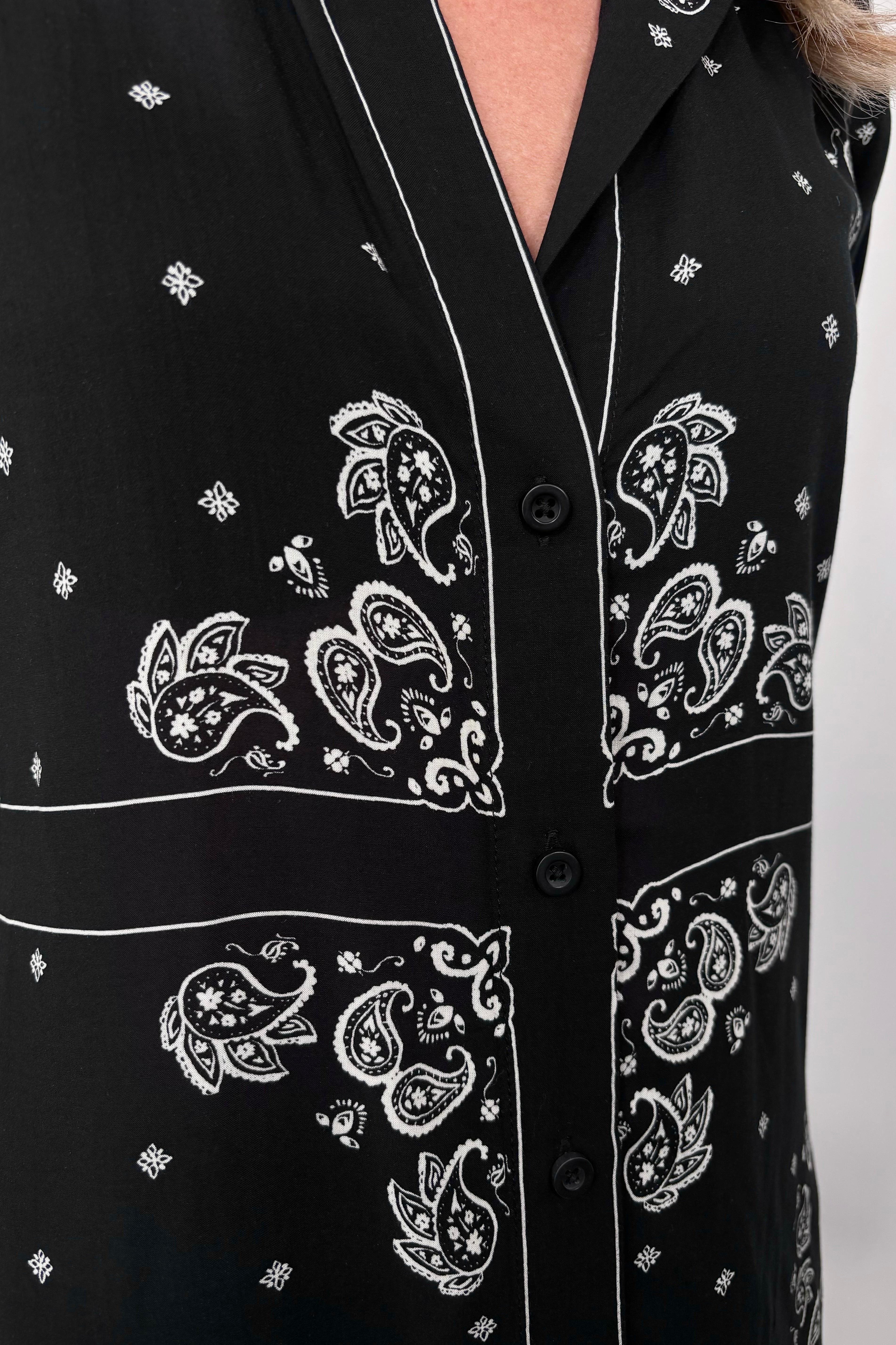 Close up view of the neckline of a bandana-patterned button down blouse