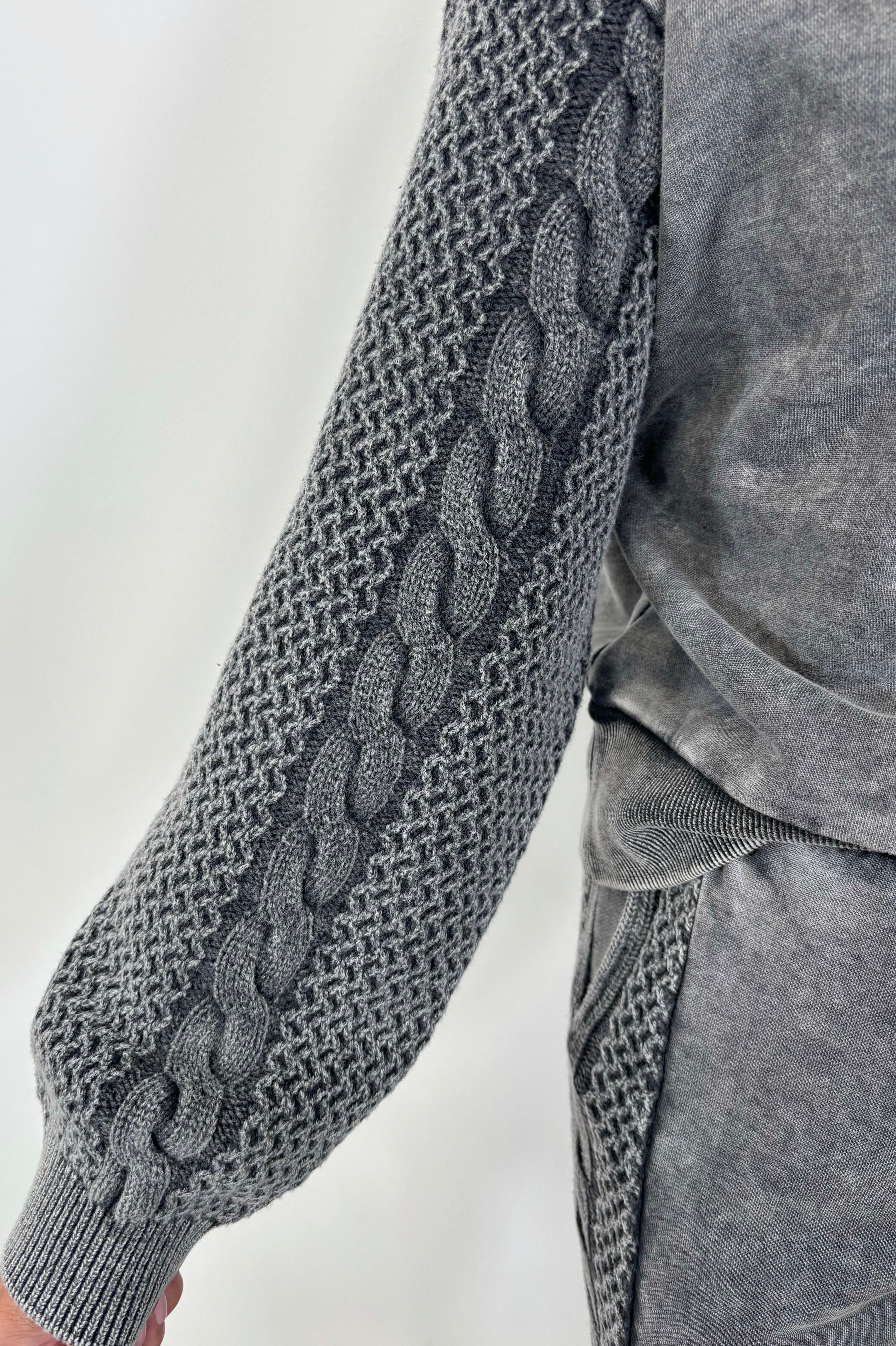 Close-up of a gray pullover sweatshirt with detailing on the sleeves