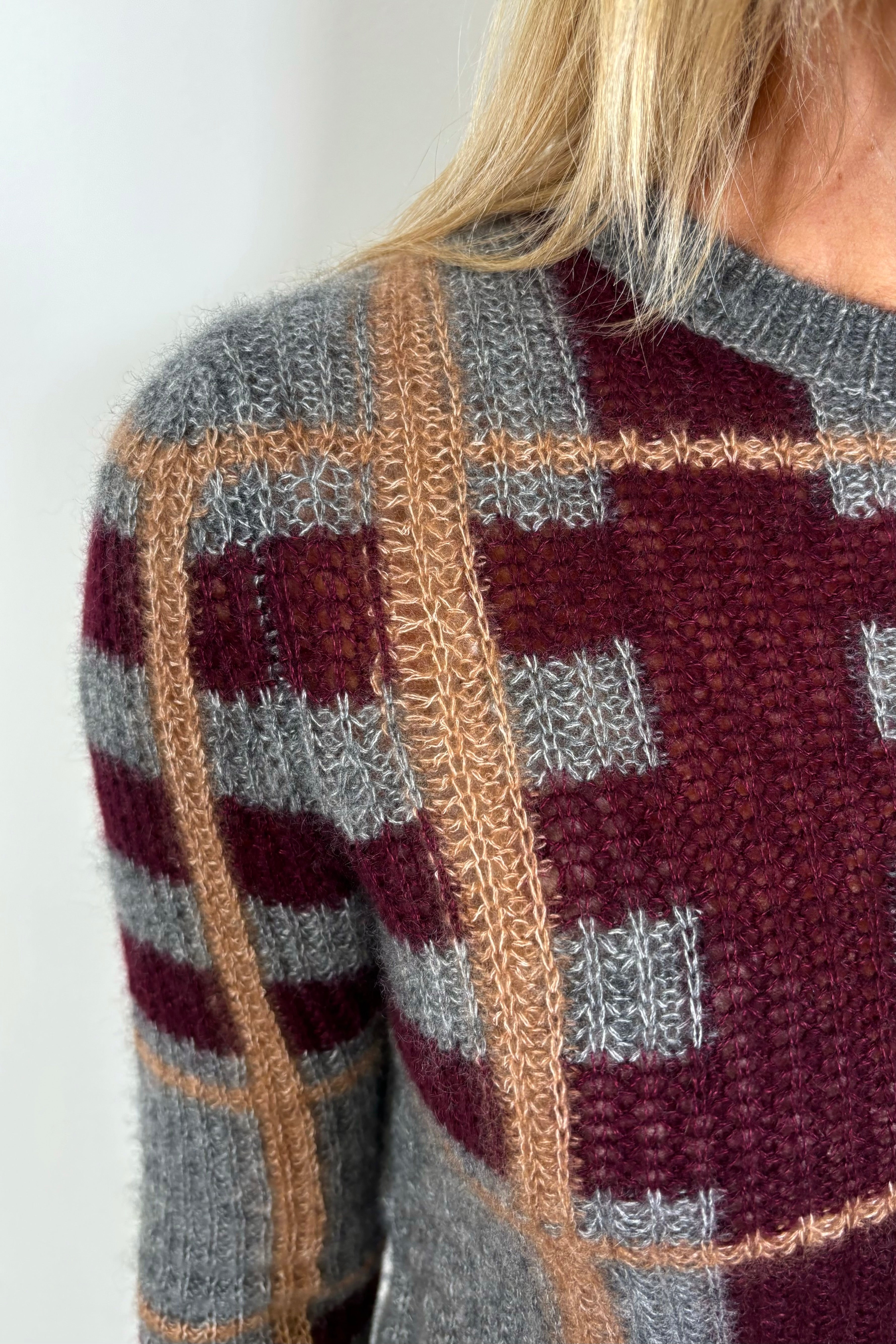 zoom in of a woman’s right shoulder showing the plaid of the gray plaided silk and cashmere sweater blend she wears