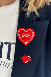 Close up of Woman wearing a navy blue blazer with gold buttons and patch details
