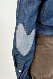 Woman wearing a blue denim shirt with brown heart patches on the elbow