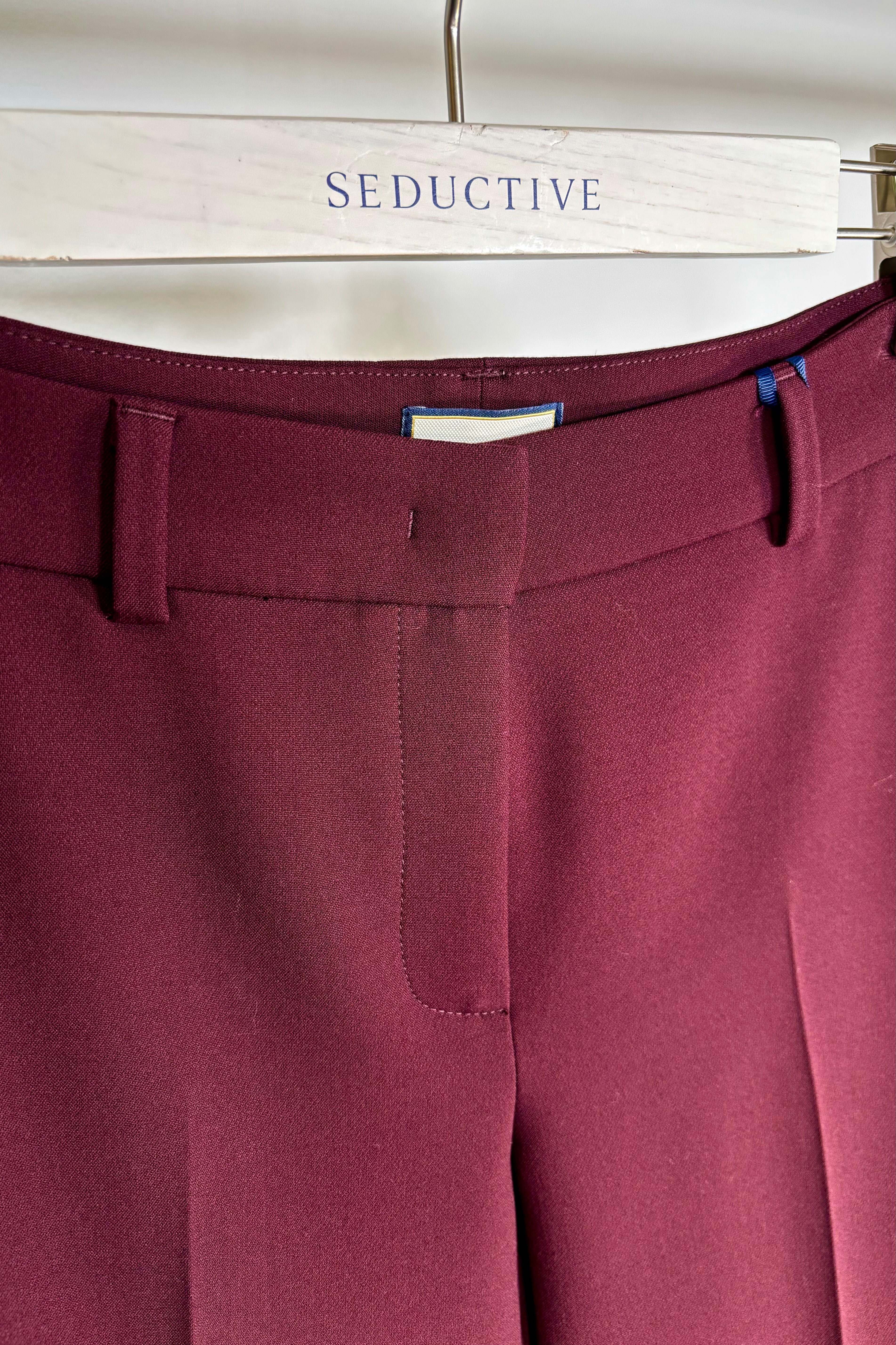 Burgundy pants on a hanger with 'SEDUCITIVE' branding.
