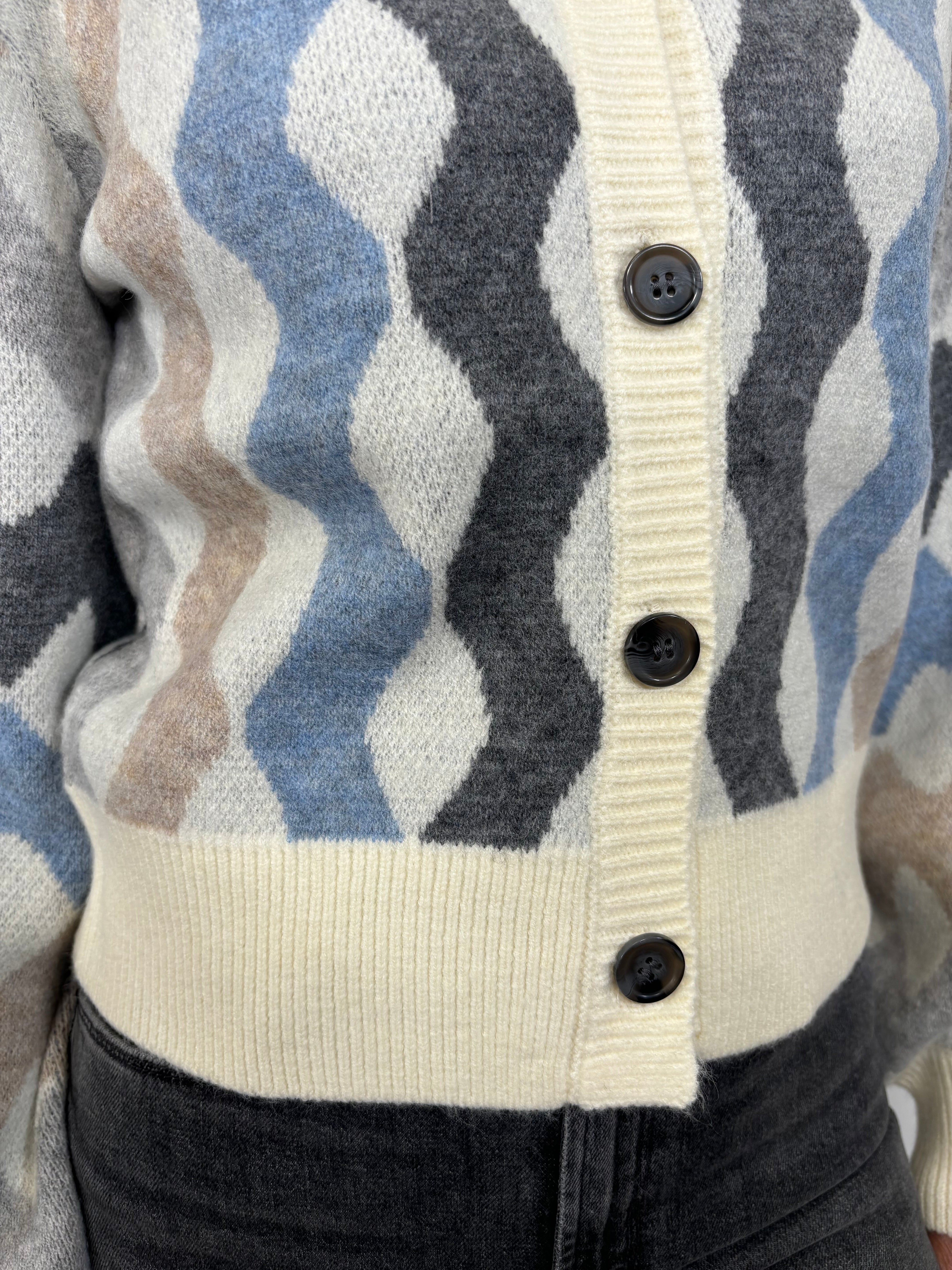 Close up view of woman wearing a cardigan with blouson sleeved and a multicoloured waive design