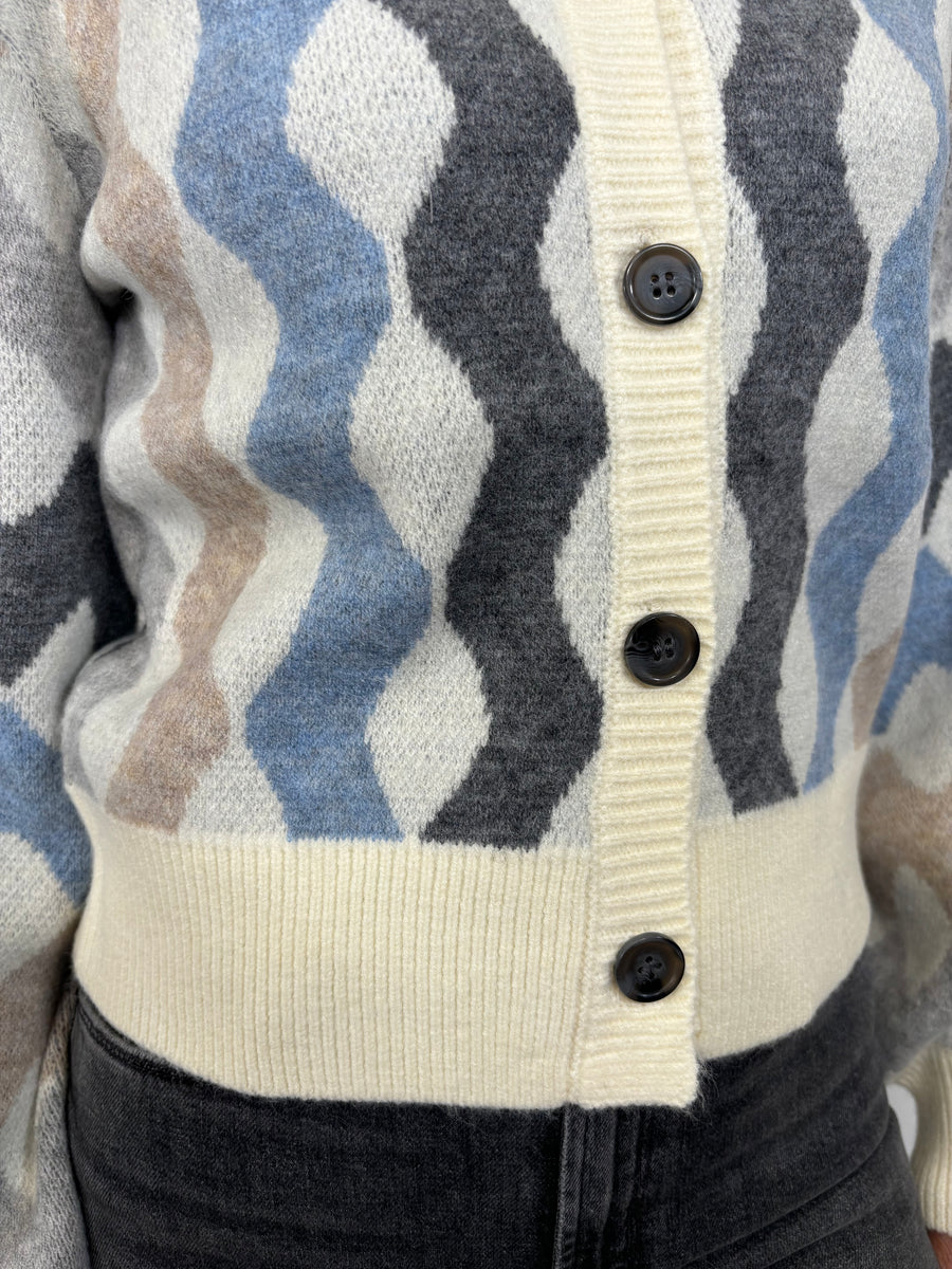Close up view of woman wearing a cardigan with blouson sleeved and a multicoloured waive design