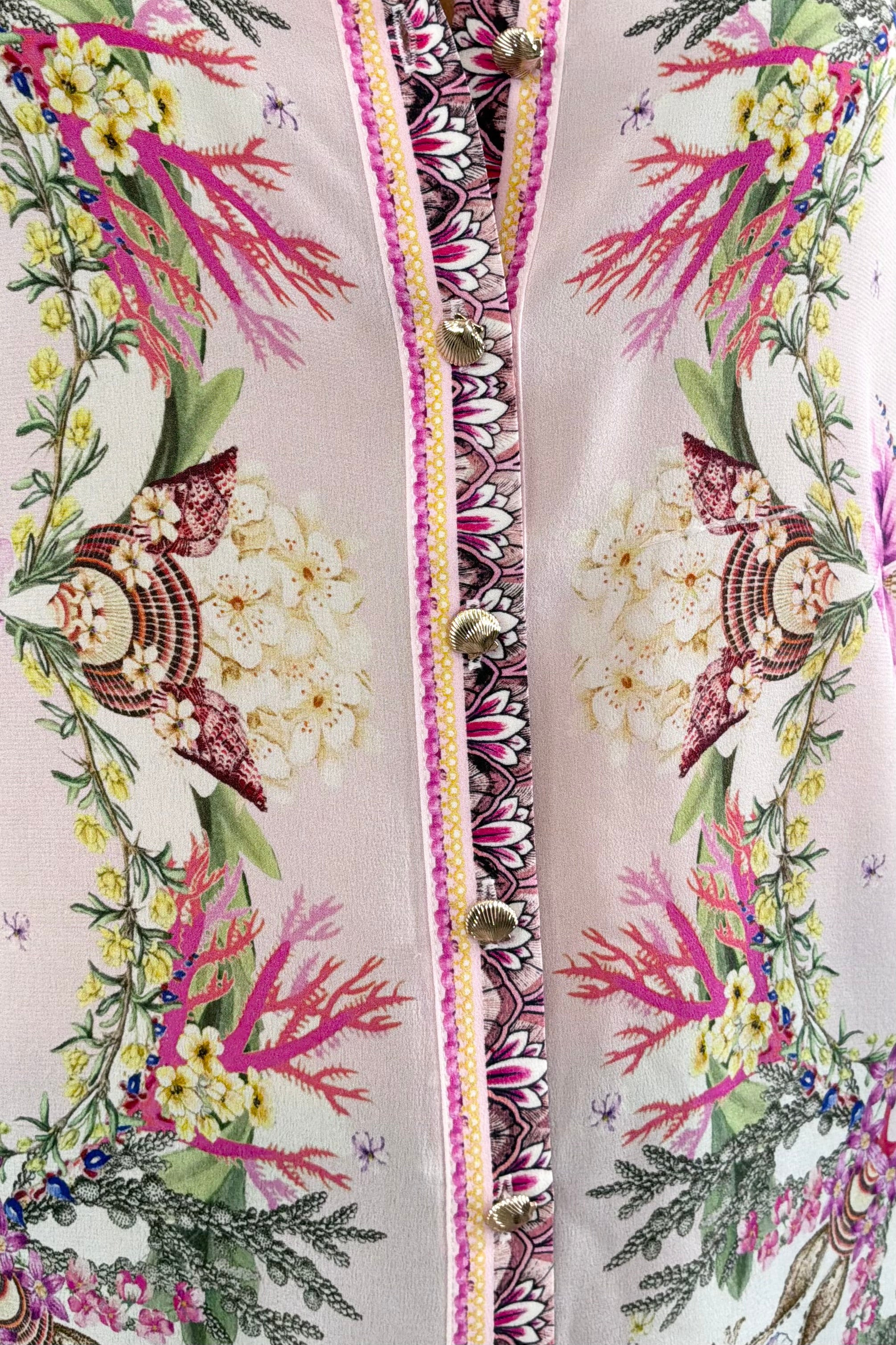 Woman wearing a floral blouse with a shell pattern 